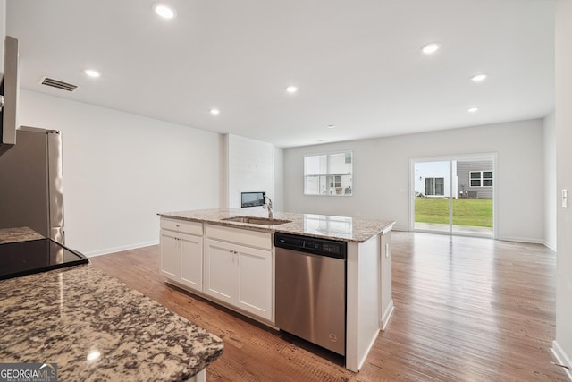 5207 Canberra Dr, Flowery Branch, GA 30542 - kitchen with stainless steel appliances, white cabinetry, an island with sink, light wood finished floors, and light stone counters