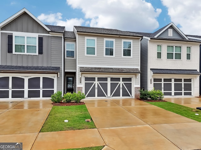 5207 Canberra Dr, Flowery Branch, GA 30542 - townhome / multi-family property featuring an attached garage, driveway, board and batten siding, and brick siding