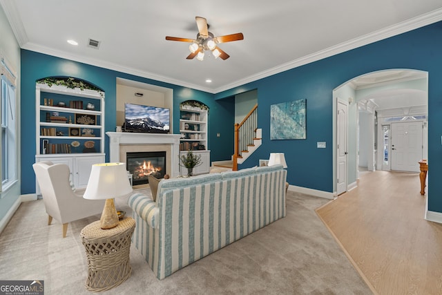 1210 Magnolia Park Cir, Cumming, GA 30040 - carpeted living room with ornamental molding, a ceiling fan, a glass covered fireplace, built in shelves, and recessed lighting