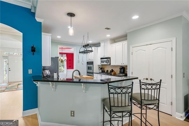 1210 Magnolia Park Cir, Cumming, GA 30040 - kitchen with appliances with stainless steel finishes, dark countertops, a breakfast bar area, light wood-style flooring, and decorative backsplash