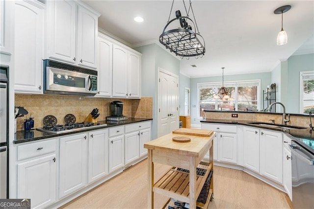 1210 Magnolia Park Cir, Cumming, GA 30040 - kitchen featuring a sink, appliances with stainless steel finishes, crown molding, white cabinetry, and hanging light fixtures