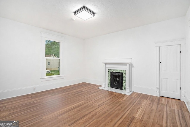 1852 Burwell Rd, Carrollton, GA 30117 - unfurnished living room featuring wood finished floors, a tile fireplace, and baseboards