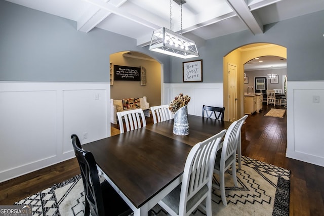 101 High Bluff Trl, Carrollton, GA 30116 - dining space featuring wainscoting, dark wood-type flooring, beam ceiling, arched walkways, and a decorative wall