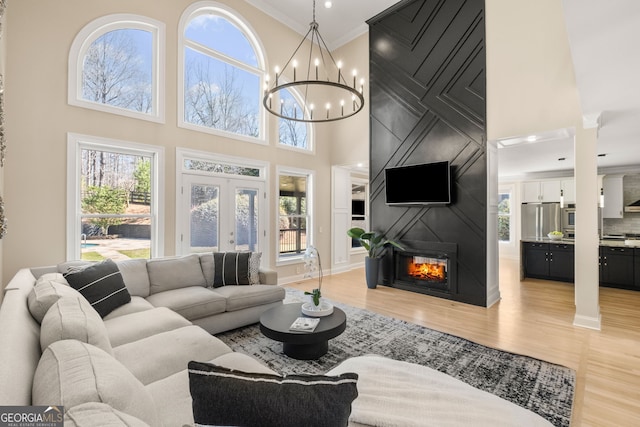 410 S Burgess Trl, Milton, GA 30004 - living room featuring a high ceiling, light wood-style floors, ornamental molding, a chandelier, and a fireplace