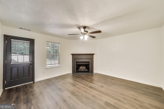 131 Turning Pt, Stockbridge, GA 30281 - unfurnished living room with a ceiling fan, wood finished floors, a fireplace with flush hearth, and a textured ceiling