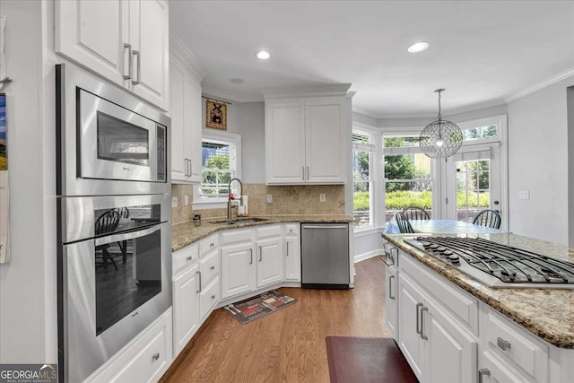 3400 Dencrest Ct SE, Smyrna, GA 30080 - kitchen featuring stainless steel appliances, light wood finished floors, a sink, white cabinets, and tasteful backsplash