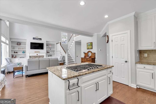 3400 Dencrest Ct SE, Smyrna, GA 30080 - kitchen with stainless steel gas stovetop, crown molding, light wood finished floors, a kitchen island, and backsplash