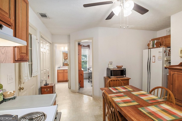 844 Potomac Pl, Winder, GA 30680 - kitchen featuring stainless steel microwave, freestanding refrigerator, light floors, a ceiling fan, and brown cabinets