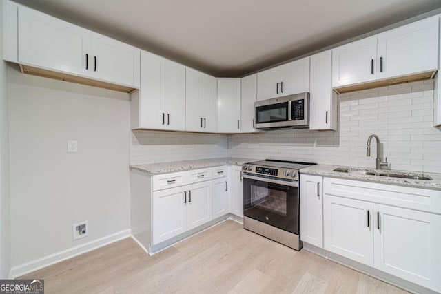 3404 Broxton Mill Way, Snellville, GA 30039 - kitchen with appliances with stainless steel finishes, light wood-style floors, light stone countertops, and white cabinetry