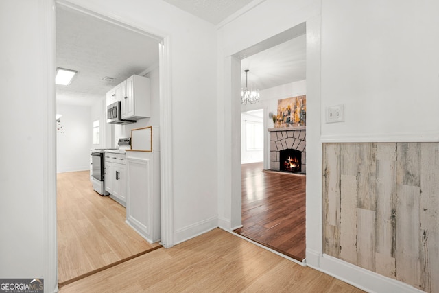 6802 Ida St, Lithonia, GA 30058 - hallway featuring light wood-style flooring and a chandelier