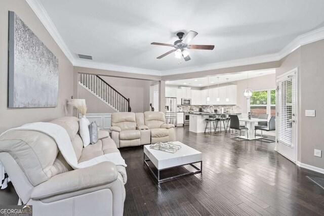 2939 Woodward Down Trl, Buford, GA 30519 - living room featuring ceiling fan, ornamental molding, stairway, and dark wood finished floors