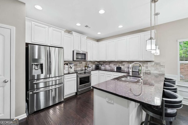 2939 Woodward Down Trl, Buford, GA 30519 - kitchen featuring appliances with stainless steel finishes, a sink, a peninsula, dark stone counters, and white cabinets