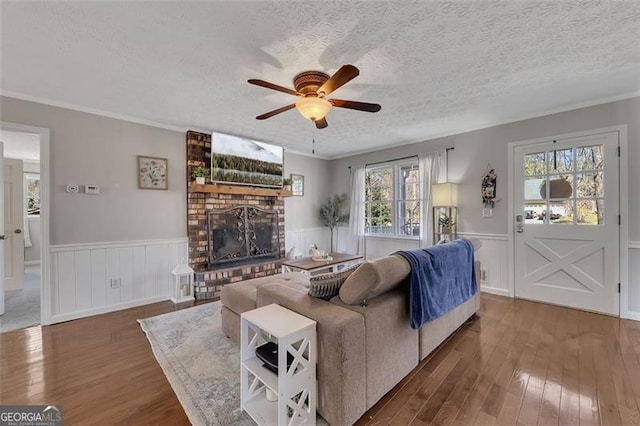 3271 Sutcliffe Rdg, Marietta, GA 30064 - living room with ceiling fan, a brick fireplace, a wainscoted wall, wood-type flooring, and a textured ceiling