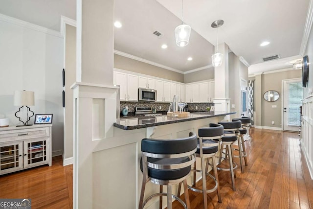 1858 Preserve Way, Atlanta, GA 30341 - kitchen with stainless steel appliances, ornamental molding, a kitchen bar, decorative backsplash, and white cabinets