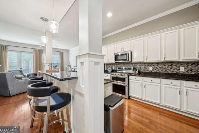 1858 Preserve Way, Atlanta, GA 30341 - kitchen featuring appliances with stainless steel finishes, a kitchen breakfast bar, open floor plan, white cabinets, and ornamental molding