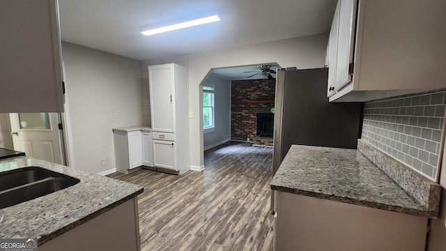 4326 Ga Highway 109, Molena, GA 30258 - kitchen with ceiling fan, dark wood-style floors, a brick fireplace, light stone counters, and white cabinetry