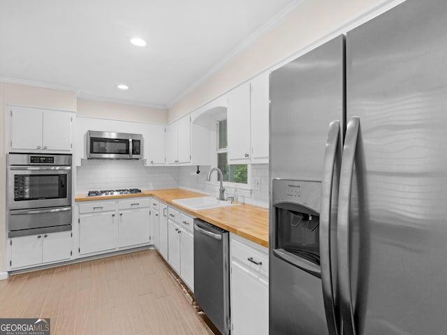 117 Thomas St, Griffin, GA 30224 - kitchen with stainless steel appliances, a warming drawer, a sink, white cabinetry, and crown molding