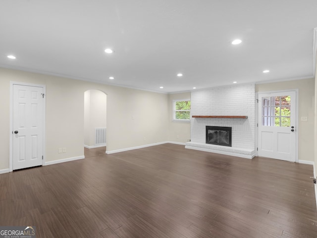 117 Thomas St, Griffin, GA 30224 - unfurnished living room with arched walkways, plenty of natural light, a brick fireplace, dark wood finished floors, and recessed lighting