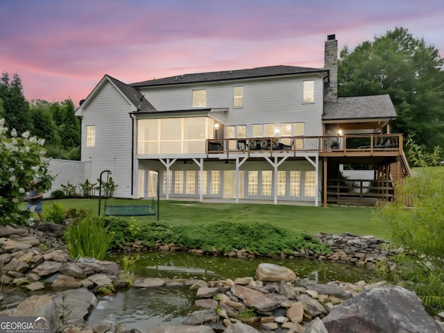 590 Arthur Rd, Canton, GA 30115 - back of house at dusk featuring a wooden deck, stairway, a yard, a chimney, and a sunroom