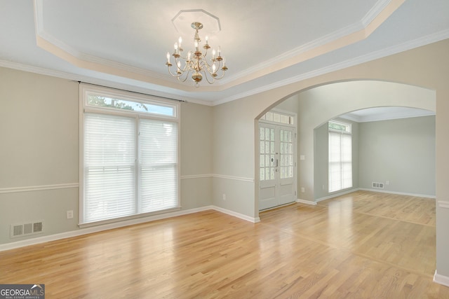 165 Hidden Lake Dr, Fayetteville, GA 30215 - empty room with a chandelier, arched walkways, a tray ceiling, light wood finished floors, and ornamental molding