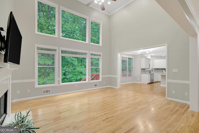 165 Hidden Lake Dr, Fayetteville, GA 30215 - unfurnished living room featuring a towering ceiling, ceiling fan, light wood-style flooring, baseboards, and a fireplace with flush hearth
