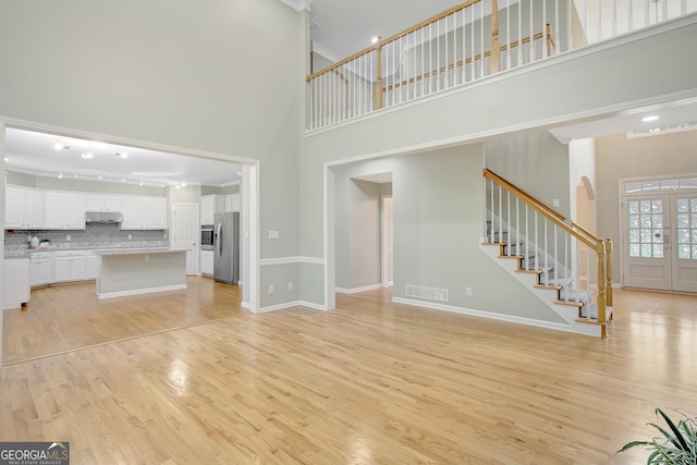 165 Hidden Lake Dr, Fayetteville, GA 30215 - unfurnished living room featuring a towering ceiling, stairway, light wood-style floors, arched walkways, and baseboards