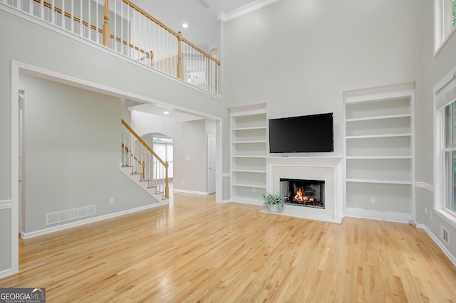 165 Hidden Lake Dr, Fayetteville, GA 30215 - unfurnished living room with a towering ceiling, stairway, wood finished floors, a warm lit fireplace, and baseboards