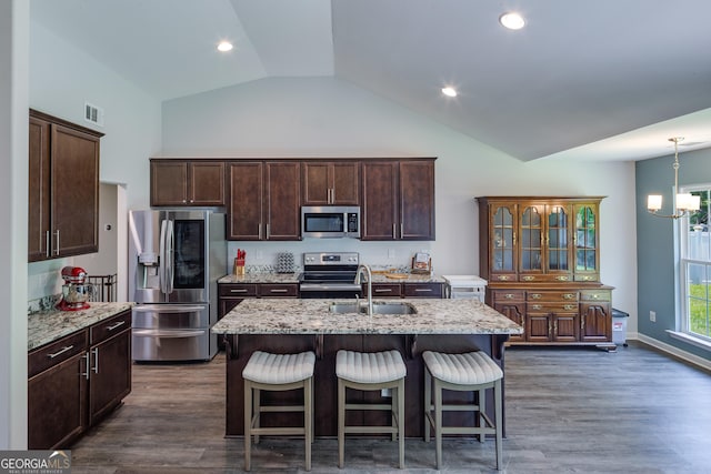 104 Johansen Way, Kingsland, GA 31548 - kitchen featuring appliances with stainless steel finishes, dark brown cabinets, high vaulted ceiling, light stone counters, and a breakfast bar
