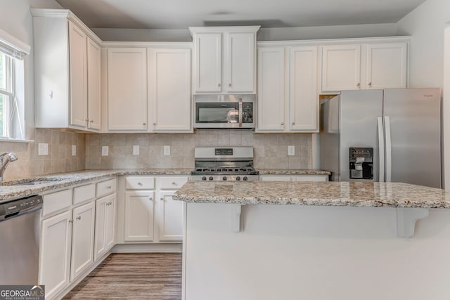 31 Blarneystone Way, Adairsville, GA 30103 - kitchen with stainless steel appliances, a sink, white cabinetry, decorative backsplash, and a breakfast bar