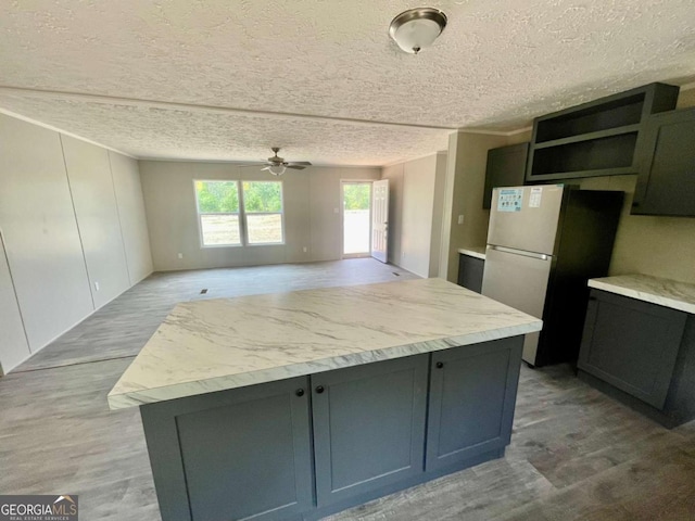 429 Avant Rd, Eatonton, GA 31024 - kitchen with a ceiling fan, light countertops, open shelves, freestanding refrigerator, and a textured ceiling