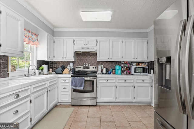 1055 Wrens Hwy, Thomson, GA 30824 - kitchen featuring appliances with stainless steel finishes, a sink, under cabinet range hood, tile counters, and white cabinets