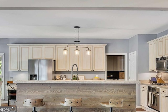 320 Ironhill Trce, Woodstock, GA 30189 - kitchen with stainless steel appliances, a sink, pendant lighting, cream cabinetry, and a kitchen bar