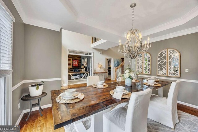 320 Ironhill Trce, Woodstock, GA 30189 - dining space featuring wood finished floors, a raised ceiling, a chandelier, crown molding, and stairway