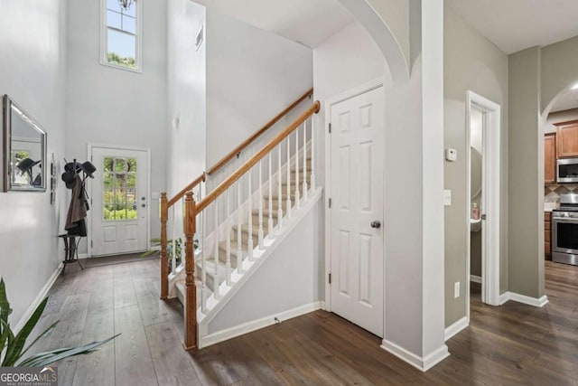 2910 Cross Creek Dr, Cumming, GA 30040 - foyer featuring arched walkways, dark wood-style flooring, stairs, baseboards, and a towering ceiling