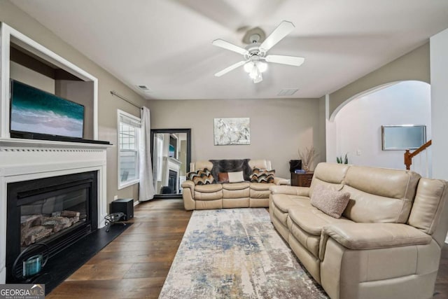 2910 Cross Creek Dr, Cumming, GA 30040 - living room featuring a glass covered fireplace, dark wood-style floors, ceiling fan, and arched walkways