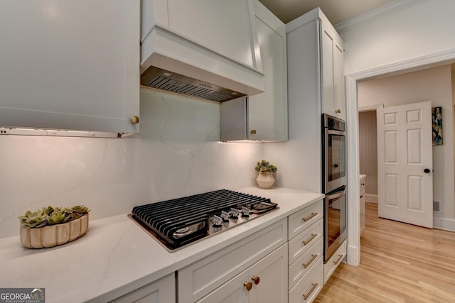 7920 Tintern Trce Unit 298, Duluth, GA 30097 - kitchen with stainless steel appliances, light wood finished floors, premium range hood, white cabinetry, and crown molding