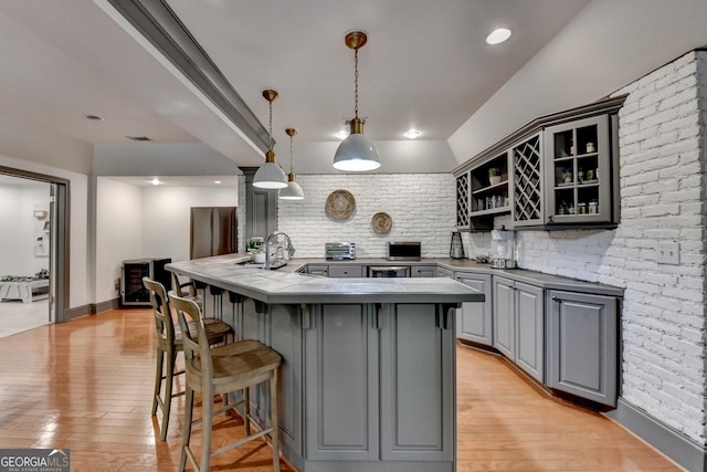 7920 Tintern Trce Unit 298, Duluth, GA 30097 - kitchen with gray cabinets, a kitchen breakfast bar, open shelves, light wood-style flooring, and backsplash