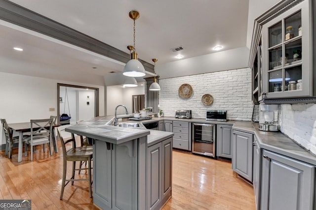 7920 Tintern Trce Unit 298, Duluth, GA 30097 - kitchen featuring gray cabinetry, beverage cooler, a sink, a kitchen breakfast bar, and backsplash