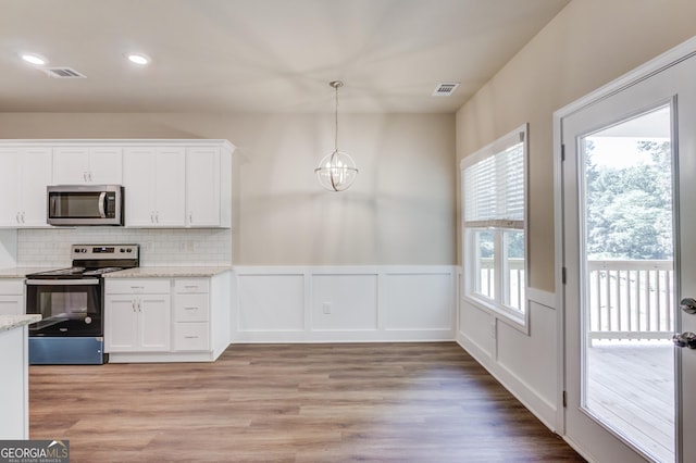 6413 River Plantation Dr, Lula, GA 30554 - kitchen with appliances with stainless steel finishes, white cabinetry, a chandelier, tasteful backsplash, and a wainscoted wall