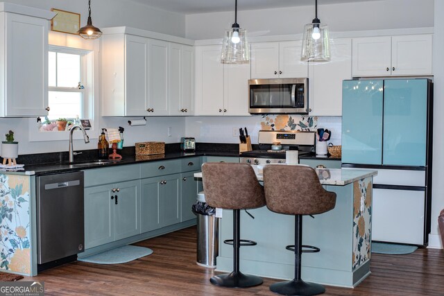 2980 Hd Atha Rd, Covington, GA 30014 - kitchen featuring stainless steel appliances, a sink, dark wood-style floors, decorative light fixtures, and white cabinets