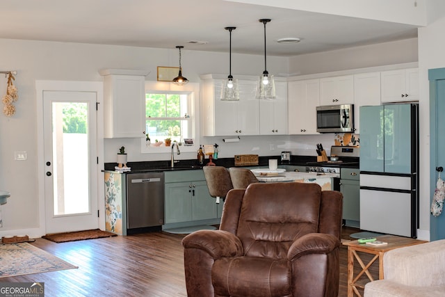 2980 Hd Atha Rd, Covington, GA 30014 - kitchen with appliances with stainless steel finishes, white cabinets, dark wood-style flooring, a sink, and hanging light fixtures