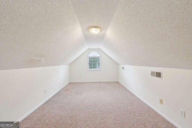 1535 Lake Dow Rd, Mcdonough, GA 30252 - bonus room with carpet flooring, lofted ceiling, and a textured ceiling