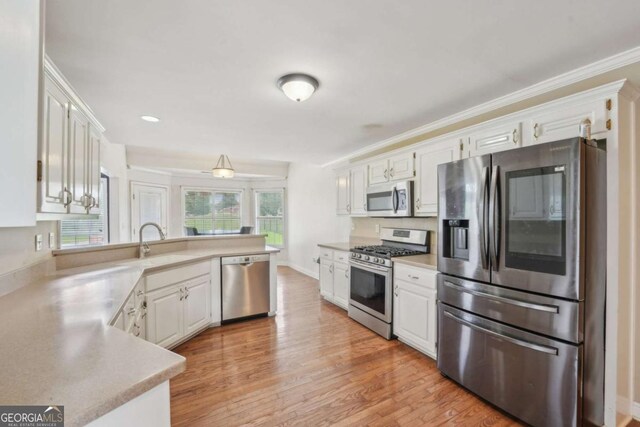 1535 Lake Dow Rd, Mcdonough, GA 30252 - kitchen featuring appliances with stainless steel finishes, a peninsula, white cabinetry, and ornamental molding