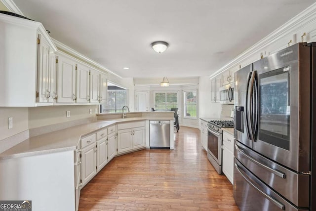 1535 Lake Dow Rd, Mcdonough, GA 30252 - kitchen with appliances with stainless steel finishes, a peninsula, light countertops, light wood-type flooring, and white cabinets