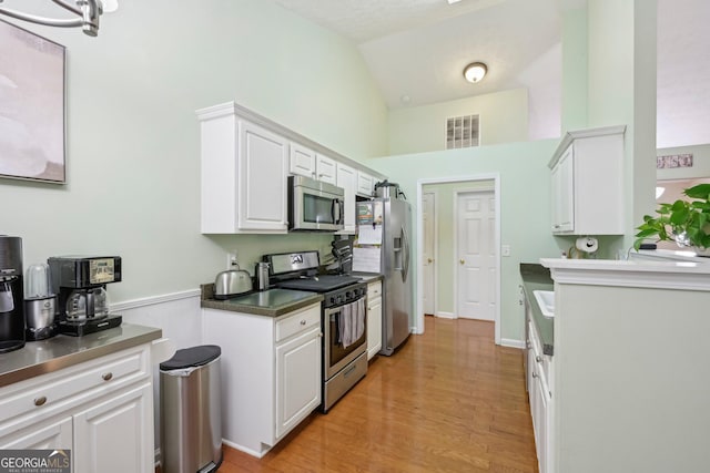 198 Lake Cv, Approach, Newnan, GA 30265 - kitchen with stainless steel appliances, white cabinets, light wood-style flooring, and vaulted ceiling