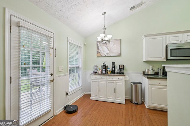 198 Lake Cv, Approach, Newnan, GA 30265 - kitchen featuring stainless steel microwave, a chandelier, vaulted ceiling, white cabinets, and a wainscoted wall