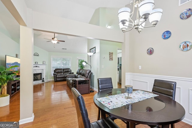 198 Lake Cv, Approach, Newnan, GA 30265 - dining room featuring a ceiling fan, a chandelier, a wainscoted wall, a fireplace, and light wood-style floors