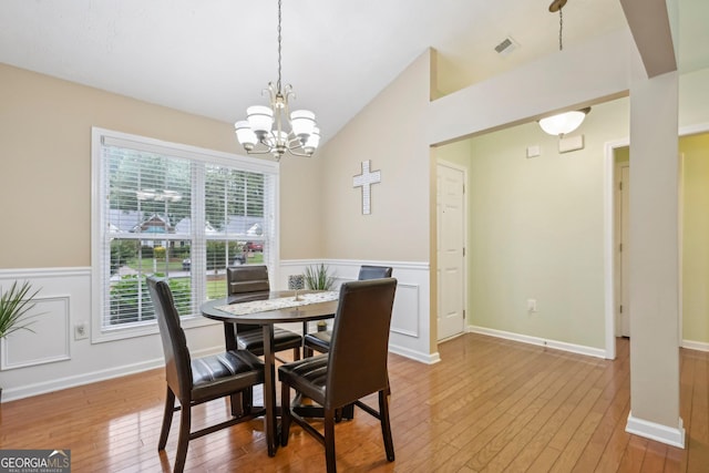 198 Lake Cv, Approach, Newnan, GA 30265 - dining area with light wood-style floors, wainscoting, a chandelier, lofted ceiling, and a decorative wall
