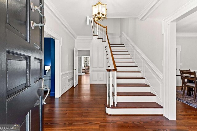 135 Mill Race Rd, Thomaston, GA 30286 - entryway featuring stairs, crown molding, a decorative wall, dark wood-style floors, and a chandelier