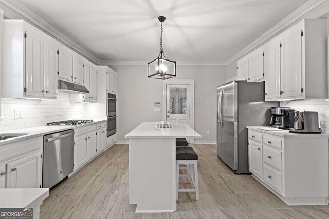 135 Mill Race Rd, Thomaston, GA 30286 - kitchen featuring appliances with stainless steel finishes, a center island, white cabinetry, decorative backsplash, and crown molding